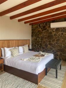 瓜达鲁佩镇Siempre Valle Hotel Boutique的一间卧室设有一张床和石墙