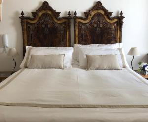 曼杜里亚Antica Casa del Pozzo的一张白色大床,配有木制床头板和枕头