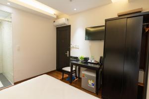 胡志明市Queen Central Hotel - Ben Thanh Market的小房间设有书桌和黑冰箱