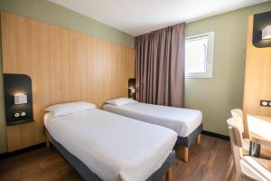 梅里尼亚克B&B HOTEL Bordeaux Mérignac Aéroport的酒店客房设有两张床和窗户。