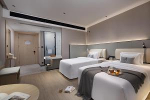 广州诗贝酒店的酒店客房设有两张床和一张桌子。