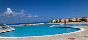 Al ḨammāmMaison sur plage的海滩上的游泳池,背景是大海