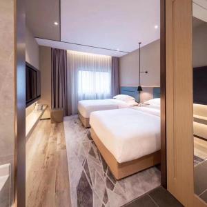 广州潮漫酒店(广州石井城市广场小坪地铁站店)的酒店客房设有两张床和电视。