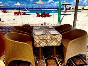 Al ḨammāmMaison sur plage的海滩上的桌子和椅子