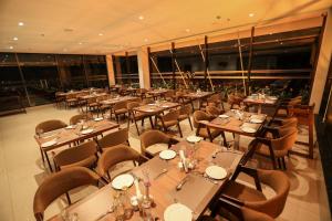 苏丹巴特利Hotel Saffron Wayanad的餐厅设有木桌、椅子和窗户。