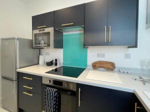 文特诺Top Deck - Fresh, stylish seaside apartment的厨房配有黑色橱柜和炉灶烤箱。