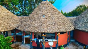 EmaliJambo Afrika Resort的茅草屋顶的小小屋,里面有一个男人
