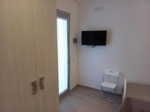 玛格丽塔萨沃亚Punta Pagliaia rooms的一间设有一扇门的房间,配有电视和椅子