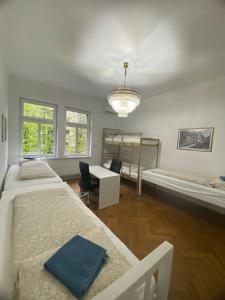 卢布尔雅那Rooms Miklošičeva的一间卧室配有两张床、一张书桌和一个吊灯。