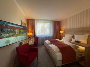 明斯特明斯特高地公园酒店的酒店客房设有一张大床和一张红色椅子。