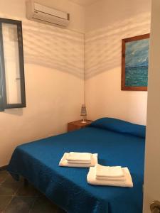 兰佩杜萨Appartamenti L'Approdo del Gabbiano的一间卧室配有蓝色的床和2条毛巾