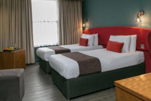 泰恩河畔纽卡斯尔Hotel Balmoral的配有红色床头板的酒店客房内的两张床