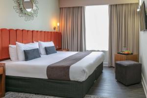 泰恩河畔纽卡斯尔Hotel Balmoral的酒店客房设有一张大床和红色床头板