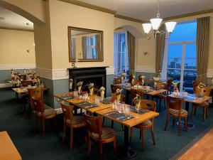斯卡伯勒大不列颠斯卡伯勒豪华酒店的餐厅设有木桌、椅子和壁炉