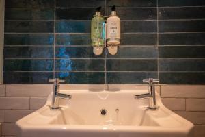 梅奈布里奇Victoria Hotel by Chef & Brewer Collection的浴室水槽和墙上的2瓶水
