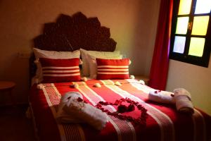 马拉喀什Riad Bab Nour的卧室配有红色和白色的床和枕头