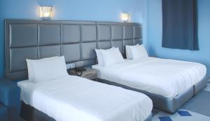 得土安Hôtel Mandy的配有白色床单的酒店客房内的两张床