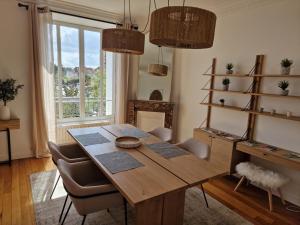 昂吉安班斯Appartement Enghien-les-Bains的一间带木桌和椅子的用餐室
