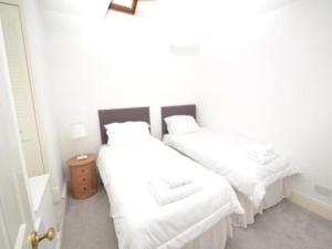 文特诺Quince Cottage的一间卧室配有两张带白色床单的床