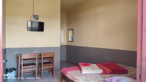布罗莫Tengger Indah Bromo by ABM的一间卧室配有一张床、一张桌子和一台电视。