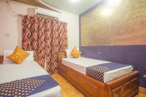 Alīpur DuārOYO Hotel Chitra的小房间设有两张床和窗帘