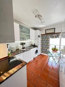 阿尔科巴萨Cocas House - Alcobaça的厨房配有白色橱柜和瓷砖地板。