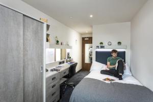 诺丁汉For Students Only Ensuite Bedrooms with Shared Kitchen at Triumph House in Nottingham的坐在卧室床上的人