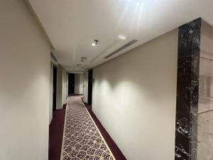 麦地那Emaar Elite Al Madina Hotel的走廊上设有白色墙壁和瓷砖地板