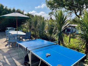 圣贾斯特Roselands Caravan Park的天井上配有带遮阳伞的蓝色乒乓球桌
