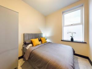 沃勒西Gibson Manor Apartment 10的一间卧室配有一张带黄色枕头的床和一扇窗户