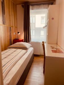 杜伊斯堡Andefu Hotel am Kantpark的一间卧室配有一张床、一张书桌和一个窗户。