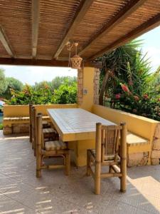 兰佩杜萨Villa Maveda, un dammuso immerso nel verde的木屋顶下的木桌和椅子
