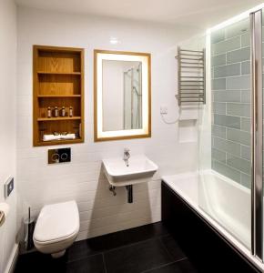 剑桥Downing College的浴室配有盥洗盆、卫生间和浴缸。