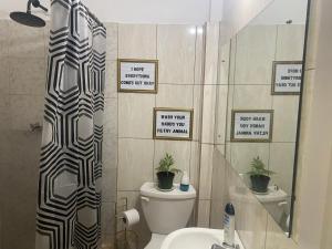 斯卡伯勒Cozy Quarters Tobago的浴室设有卫生间和墙上标志淋浴。