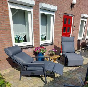 AlteveerB&B Poort van Westerwolde privé appartement met terras op zuiden的庭院设有两把椅子和一张桌子,还有一个红色的门