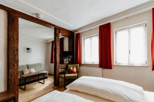 罗滕堡金吉瑞芬酒店的一间卧室配有红色窗帘、一张床和椅子
