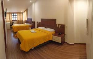 卡哈马卡Hotel Silva Inn的配有黄色床单的酒店客房的两张床