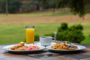 瓦斯卡坎波Hotel & Glamping Huasca Sierra Verde的一张桌子,上面放着两盘食物和一杯橙汁