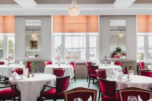 斯特兰拉尔西北城堡酒店的餐厅设有白色桌子和红色椅子,窗户