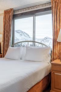 六月湖Heidelberg Inn & Resort的窗户前的一张带白色枕头的床