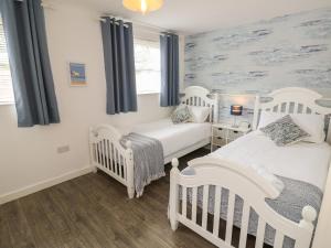 新港The Coach House的卧室配有两张白色的婴儿床和蓝色的窗帘