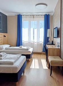 格丁尼亚Kamienica Morska Gdynia的酒店客房设有两张床、一张书桌和一个窗户。
