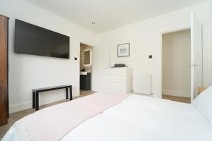 滨海韦斯顿Beach Condos的白色卧室设有一张大床和平面电视