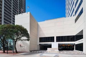 休斯顿Houston Marriott Medical Center/Museum District的一座白色的大建筑,前面有长凳