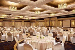 皇后区东拉瓜迪亚喜来登酒店的宴会厅配有白色的桌椅和吊灯