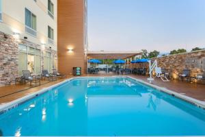 亚历山德里亚Fairfield Inn & Suites by Marriott Alexandria的一座带椅子的大型游泳池和一座建筑