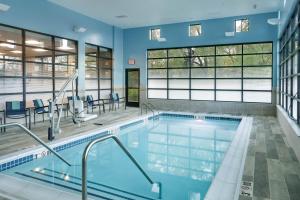 托皮卡SpringHill Suites by Marriott Topeka Southwest的一座拥有蓝色墙壁和窗户的建筑中的游泳池