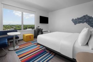 坦帕Aloft Tampa Midtown的卧室配有白色的床、桌子和窗户。