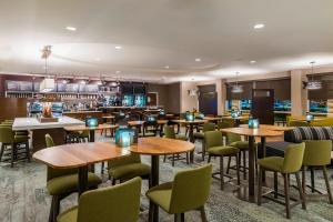 埃斯特罗迈尔斯堡75号州际公路及湾岸中心万怡酒店的餐厅设有木桌和绿色椅子