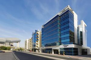 迪拜Courtyard by Marriott Dubai, Al Barsha的街道上高大的建筑,有蓝色的窗户